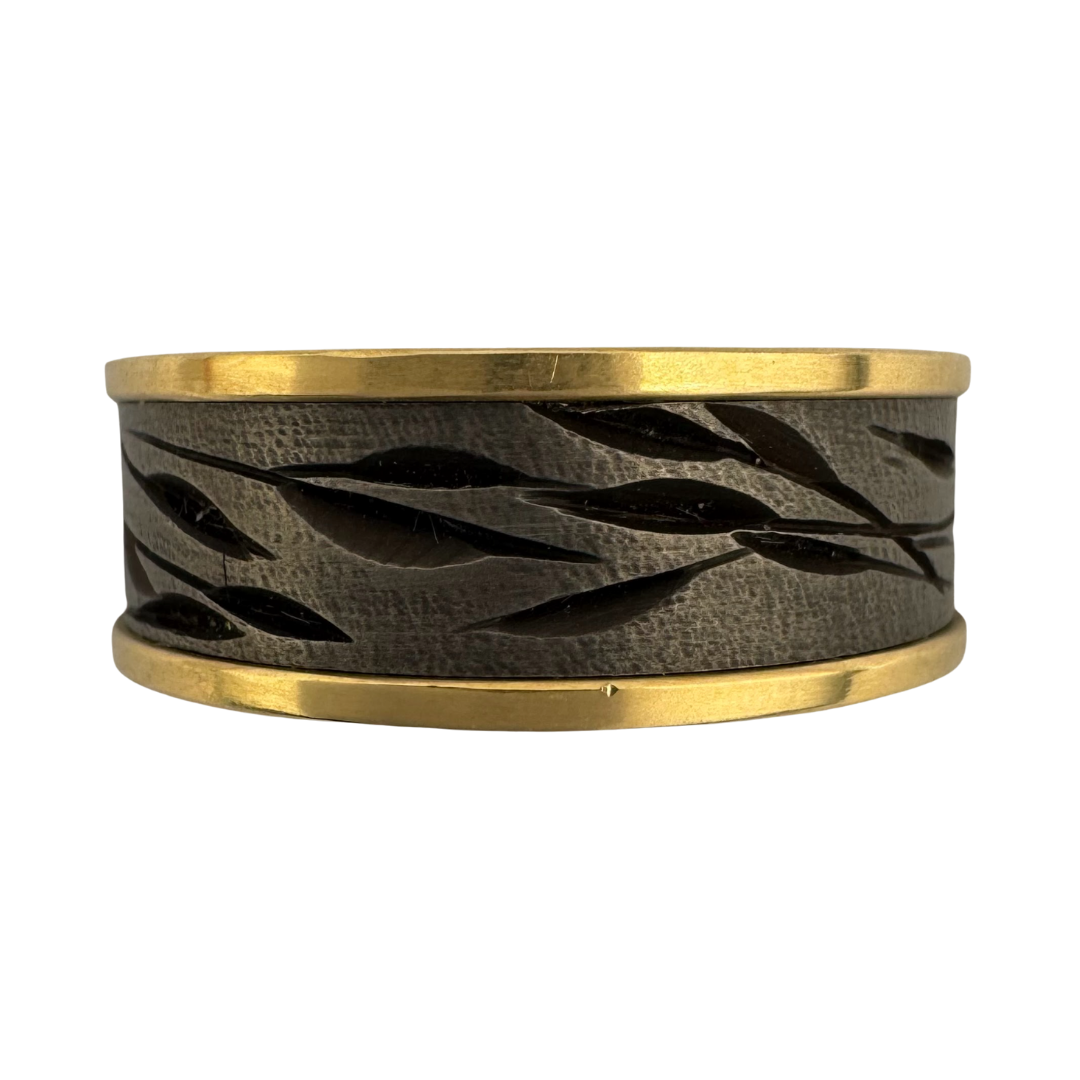 Titanium band with yellow gold shoulders and carved with random leaf and stem motif, each ring similar but different, dark grey coloring