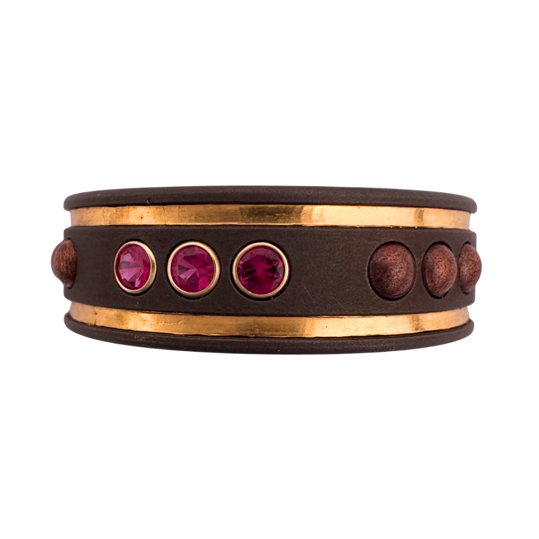 Titanium band with alternating groups of (3) 2mm rubies in gold settings with (3) copper rivets and inlays of 24K gold on either edge