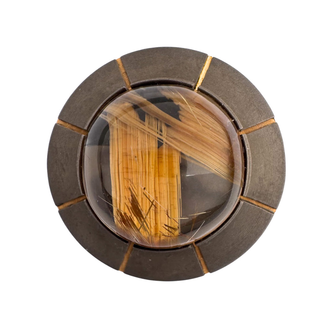 Titanium band with a 14mm smoky quartz with rutile inclusions cabochon bezel set onto a disk with radiating inlays of gold - band