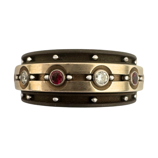 Titanium band with titanium spinner band set with (6)2mm diamonds and (6)2mm rubies in 18K white gold settings with stainless balls in outside channels and flanking the stones
