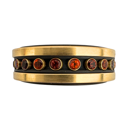 Titanium liner with (2)14K gold bands, a center titanium band set with alternating (12)2mm topaz and (12)2mm garnet set in 18K gold - all spinners